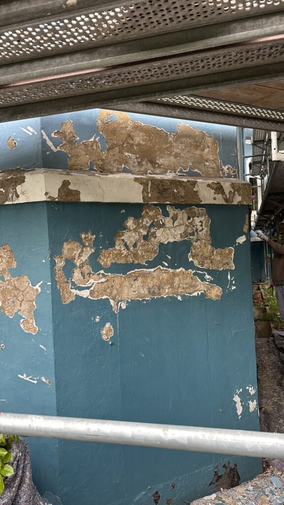 Großflächig abgeplatzter Putz und abblätternde Farbe an der Fassadenecke