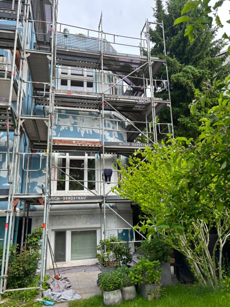 Eingerüstete Altbaufassade mit altem blauen Anstrich vor der Sanierung