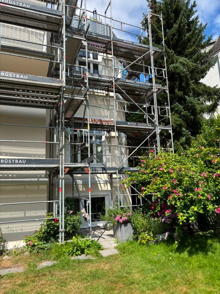 Sanierte Hausfassade im neuen hellen Farbton, Gerüst noch aufgebaut